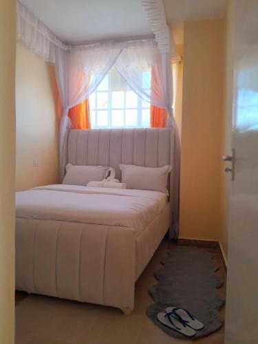 a bedroom with a white bed with a window at BnB in Homa Bay
