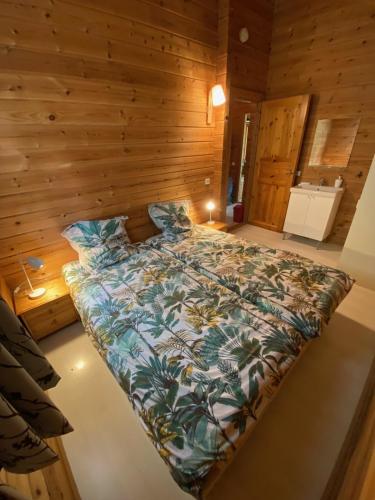 a large bed in a room with wooden walls at Chalet Chez Jeannot, N6 in Mauroux