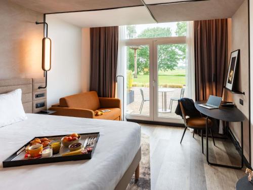a hotel room with a bed with a tray of food on it at Novotel Saint-Quentin en Yvelines in Magny-les-Hameaux