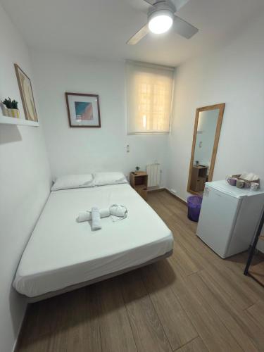 a bedroom with a white bed and a small refrigerator at Rooms Sincelejo in Madrid