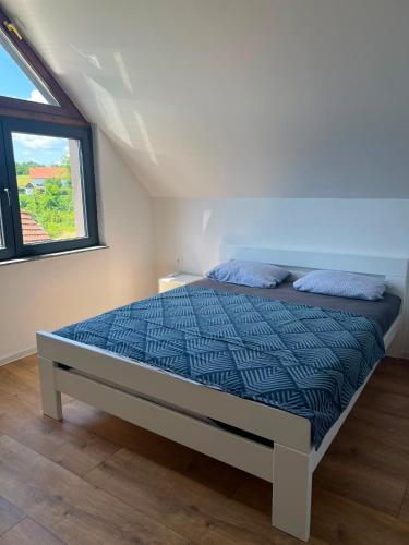 a bedroom with a bed with blue comforter and a window at Villa Jovičić in Prijedor