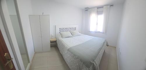 a white bedroom with a bed and a window at Casa Andrea in Puerto Real
