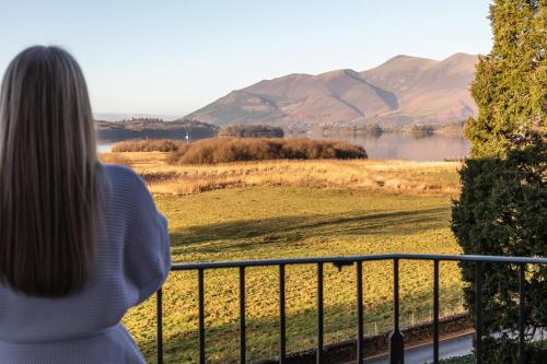 a woman standing on a balcony looking at a lake at Lodore Falls Hotel & Spa in Keswick