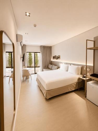 ein Schlafzimmer mit einem großen weißen Bett und einem Schreibtisch in der Unterkunft Holanda Gold Hotel Praia de Tambaú in João Pessoa