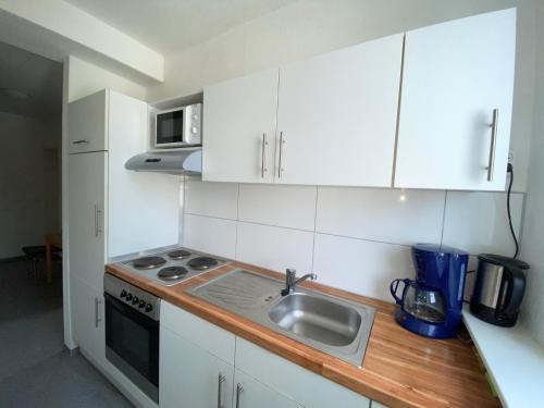 a kitchen with white cabinets and a sink and a microwave at Gästehaus Vienenburg - Monteurzimmer in Goslar