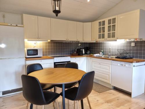 a kitchen with white cabinets and a wooden table and chairs at Forest Lodge Ryokan in Trosa