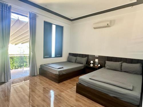 a bedroom with two beds and a window at Captain's Home Phong Nha in Phong Nha