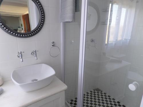 a white bathroom with a sink and a shower at Little Camelot in Langebaan