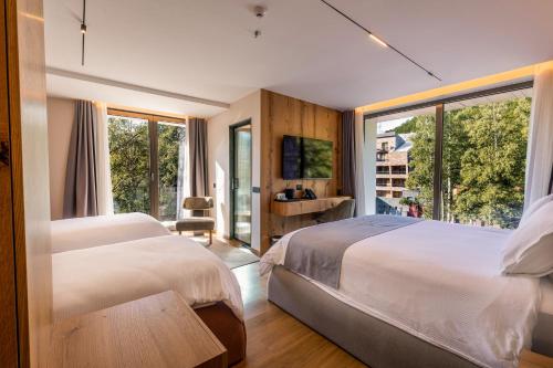 ein Schlafzimmer mit zwei Betten und einem großen Fenster in der Unterkunft Pine Hotel & Spa Brezovice in Brezovica