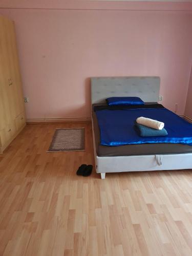 a bedroom with a bed with blue sheets and a wooden floor at Apartman Bistrivoda 2 in Vogošća
