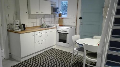 a kitchen with white cabinets and a table and a stove at Royaltybed Copenhagen in Copenhagen