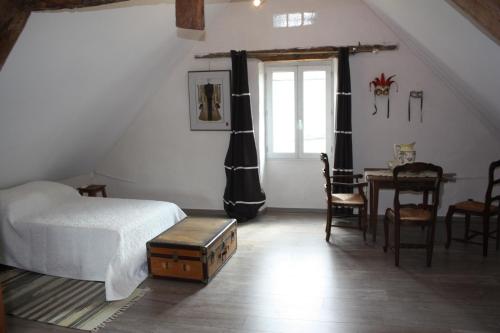 a bedroom with a bed and a table and a window at Le Jardin Aux Lilas in Cadrieu