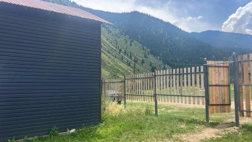 a black building with a fence in front of a mountain at Kolsay Camp House in Kurmenty