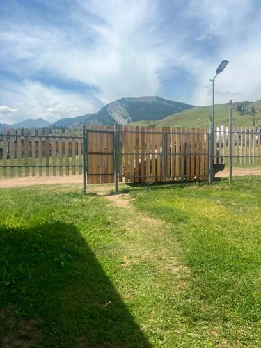 a wooden fence in a field with mountains in the background at Kolsay Camp House in Kurmenty