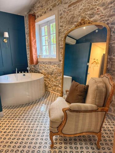 a bathroom with a tub and a chair and a mirror at Suite Sunan in Toulon