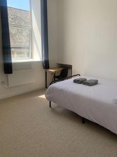 a bedroom with a bed and a desk and a window at Sunny Cottage in Camborne