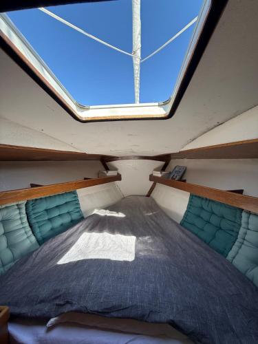 a bed in the middle of a room with a window at Fully equipped sailing boat & exploring zodiac in Nyon