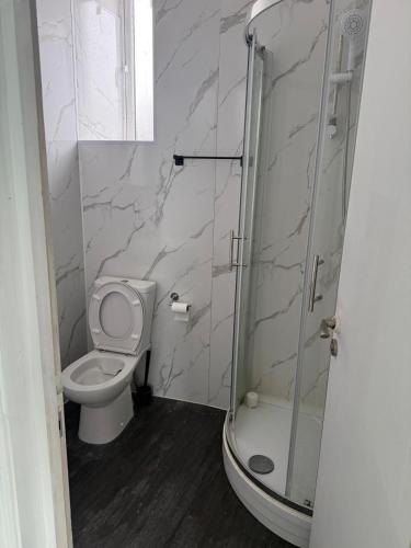 a bathroom with a toilet and a glass shower at Sunny Cottage in Camborne