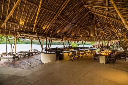 班尤温当曼加冈王朝度假酒店的一间带桌椅和大型稻草屋顶的餐厅