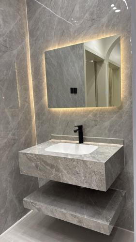 a bathroom with a marble sink and a mirror at شقة سحاب ابها in Abha