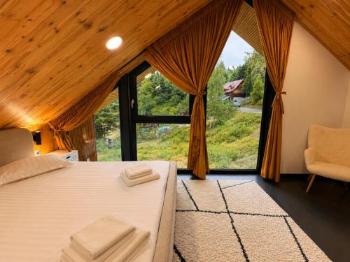 a bedroom with a bed and a large window at Norway Cabins Sinaia Romantic Nordic Escape and Fire Pit in Sinaia