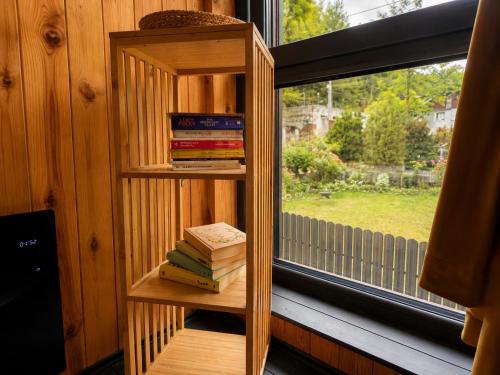 a book shelf next to a window with books at Norway Cabins Sinaia Romantic Nordic Escape and Fire Pit in Sinaia