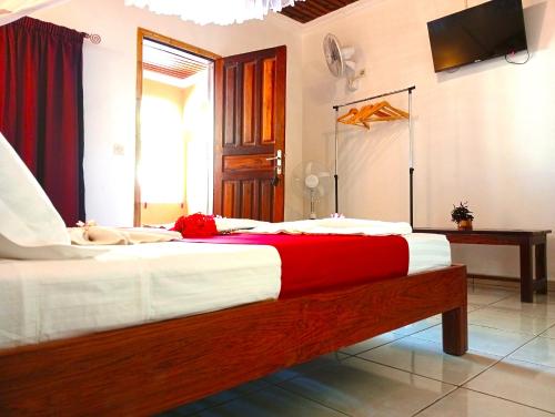 a bedroom with a large bed with red and white sheets at Fleurs d'Ylang in Nosy Be