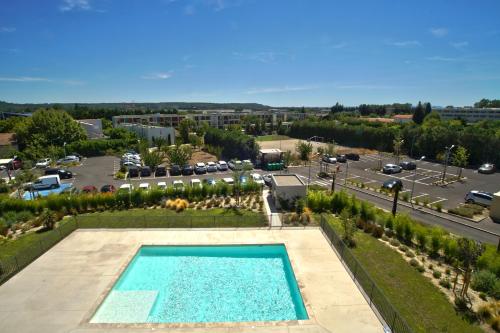an overhead view of a swimming pool with a parking lot at KOSY Appart'Hôtels - Campus Del Sol Esplanade in Montfavet