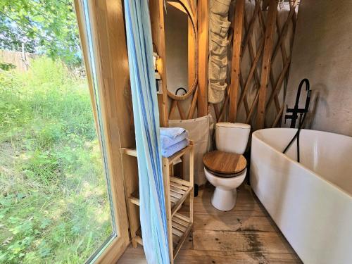 a bathroom with a toilet and a tub and a window at Ałabajka jurta i camping in Wleń