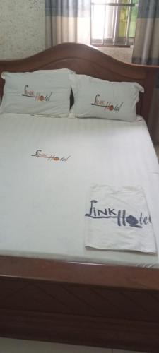 a bed with white sheets and pillows on it at Link Hotel in Lokossa