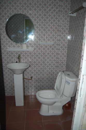 a bathroom with a toilet and a sink and a mirror at Link Hotel in Lokossa