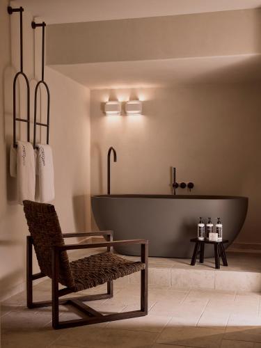 a bathroom with a bathtub and a chair and a bath tub at Ostraco Houses in Pachaina