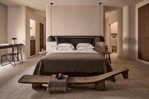 a bedroom with a large bed and a wooden bench at Ostraco Houses in Pachaina