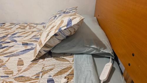 a bed with a pillow and a remote control on it at Alojamiento Centro de Punta Arenas in Punta Arenas