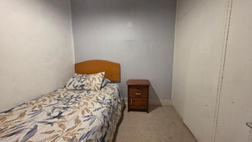 a small bedroom with a bed and a night stand at Alojamiento Centro de Punta Arenas in Punta Arenas