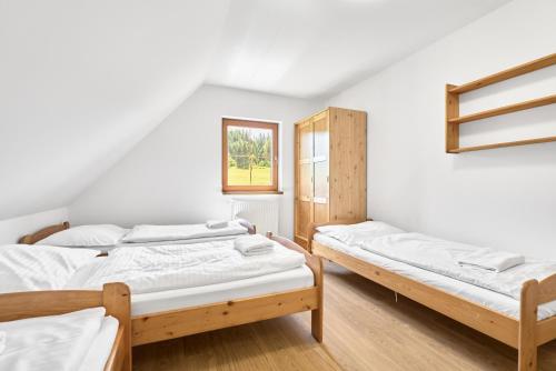 two beds in a room with white walls and wooden floors at Lenhart's Ryžovna by Mountain ways in Boží Dar
