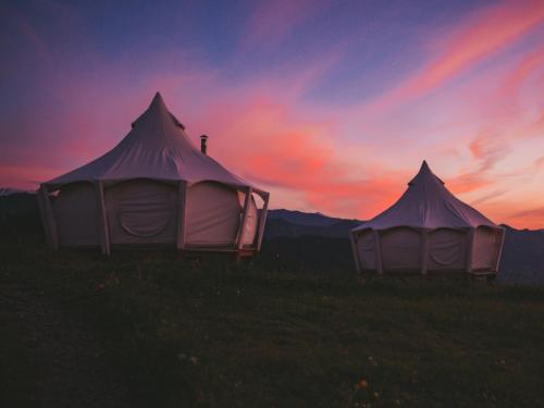 two tents in a field with a sunset in the background at Glamping Tago in Khulo