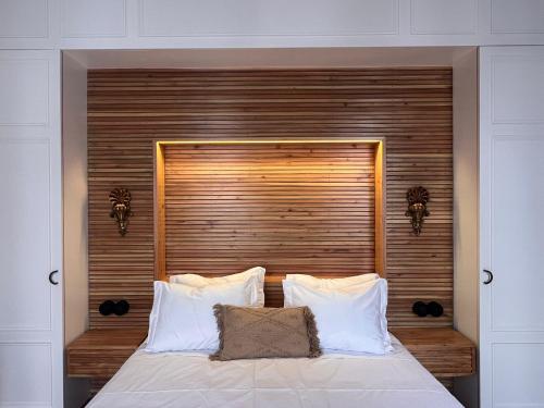 a bed with a wooden headboard and white pillows at Hommage in Horta