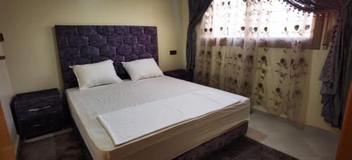 ein Schlafzimmer mit einem großen Bett und einem großen Fenster in der Unterkunft hôtel Benkachour in Oujda