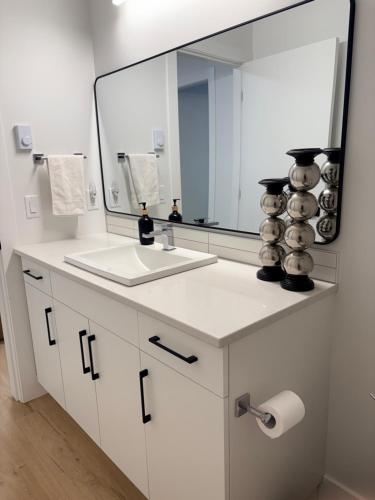 a bathroom with a sink and a large mirror at Upscale One Bedroom Suite in New Build in Kelowna