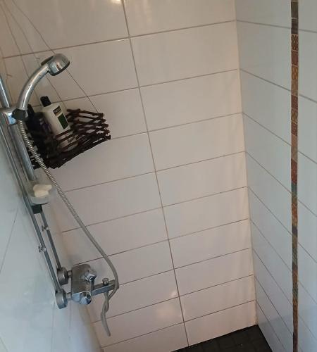 a shower in a bathroom with white tiles at Suvela in Muurame