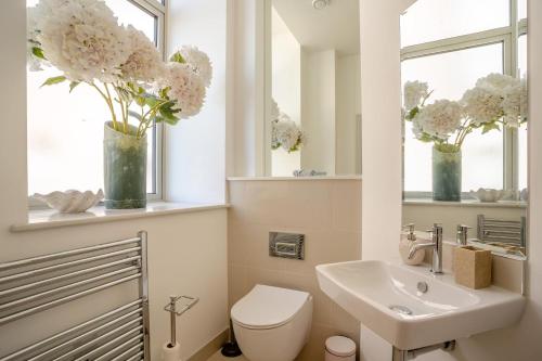 a bathroom with a toilet and a sink and vases with flowers at 2 Bed in Porthcawl oc-87294 in Porthcawl
