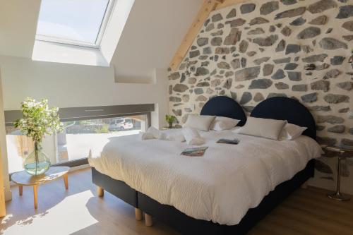 a bedroom with a large bed with a stone wall at Maison Serrioux in Cholonge
