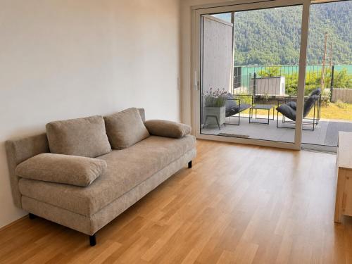 a living room with a couch and a large window at Lakeside Garden Ossiacher See in Sattendorf