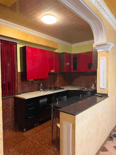 a kitchen with red cabinets and a black island at flat in Itʼkhvisi