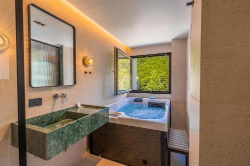 ein Badezimmer mit einer großen Steinbadewanne und einem Fenster in der Unterkunft Pine Hotel & Spa Brezovice in Brezovica