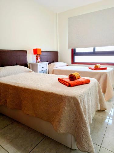 a bedroom with two beds with orange towels on them at La Ola in El Médano