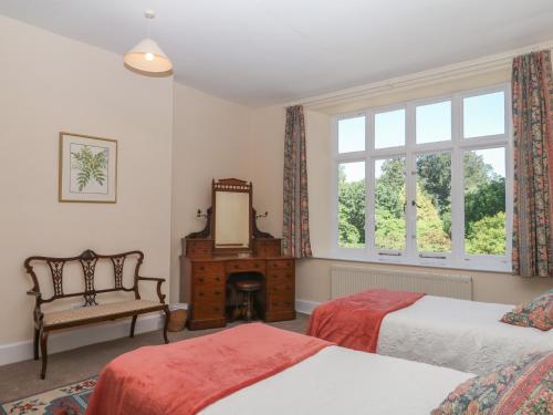 a bedroom with two beds and a mirror and a chair at Lukesland Wing in Ivybridge