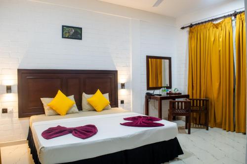 a bedroom with a large bed with yellow and red pillows at Roy's Polonnaruwa in Polonnaruwa