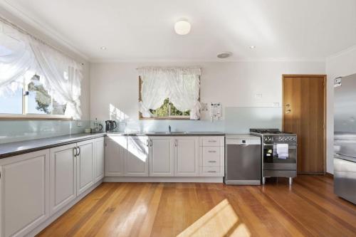 a kitchen with white appliances and a wooden floor at Eaglehawk Neck Getaway in Eaglehawk Neck